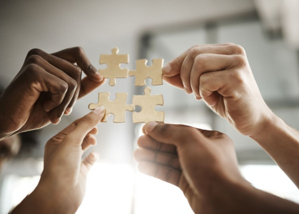 a group of hands, presumably attached to people, coming together to make a puzzle